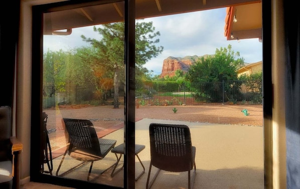 A room with a sliding glass door leading to an outdoor patio with chairs and a view of a mountainous landscape.