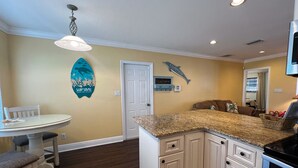 A kitchen with a granite countertop, white cabinetry, and a dining area with a white table and chairs. - Heated Pool! 2 Master Suites- 5 miles to Clearwater Beach! (Clearwater)