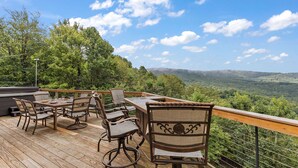 Um terraço com mobiliário de exterior e uma vista panorâmica de um vale arborizado.