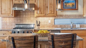 Una cocina con armarios de madera, una estufa a gas, un lavamanos y un cuadro en la pared.