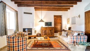 Ein gemütliches Wohnzimmer mit Kamin, Fernseher und einer Sofagarnitur.