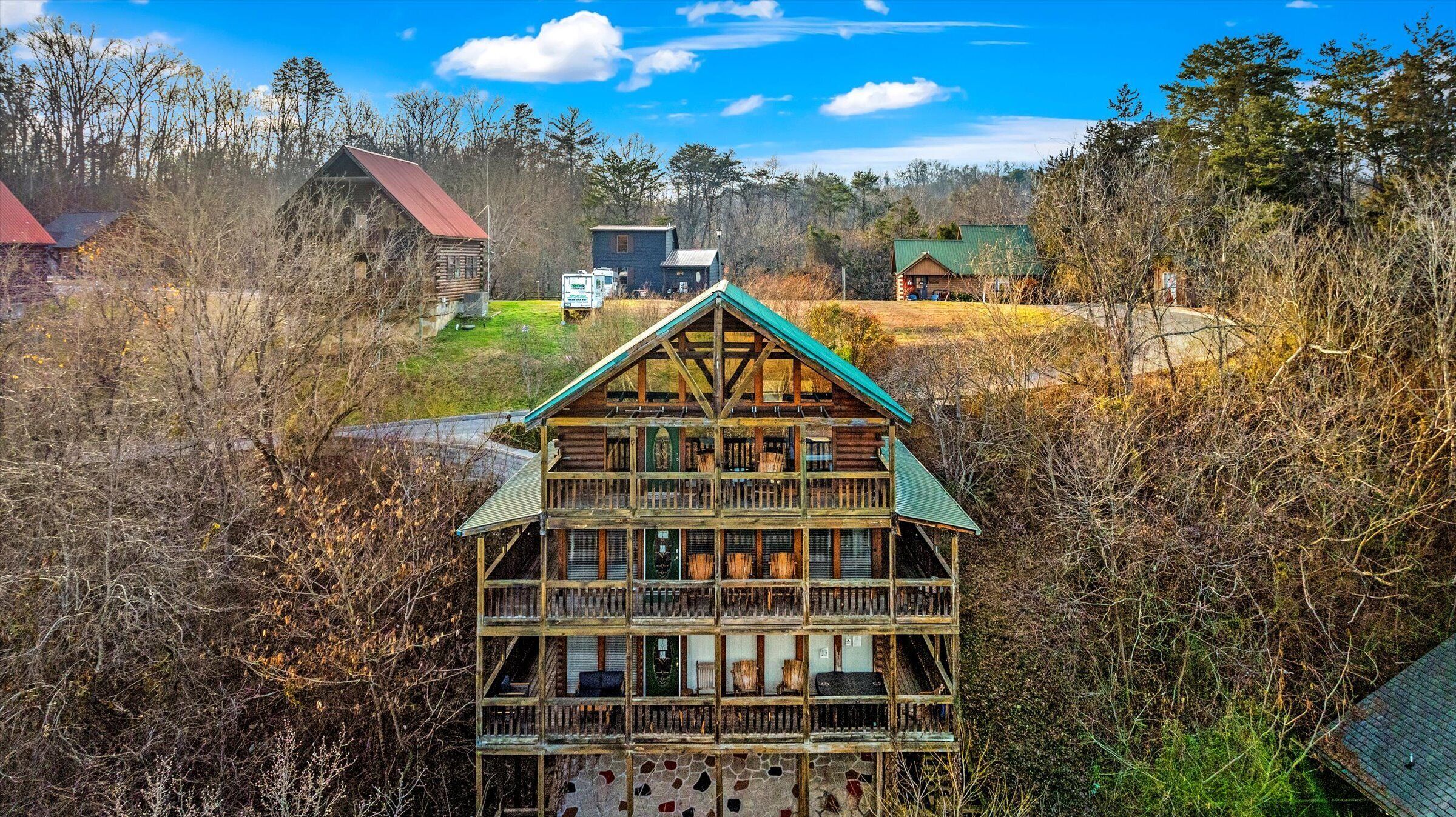 A multi-story log cabin with a green roof, surrounded by dense forest.