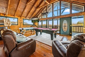 A wooden interior with a pool table, leather chairs, and large windows. - Summer Break • Theater • Hot Tub • Games • Pets Ok (Sevierville)