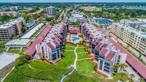 A modern hotel complex with multiple buildings, a central pool, and well-maintained green spaces. - Beachfront Condo on Famous Siesta Key! (Sarasota)