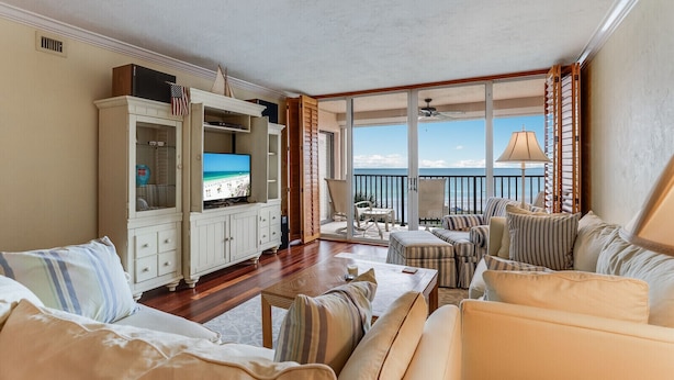 A spacious living room with a large TV, comfortable seating, and a balcony with a view of the ocean. - Beachfront Condo on Famous Siesta Key! (Sarasota)