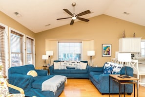 A living room with a ceiling fan, two sofas, a coffee table, and a window with blinds. - Over The Moon - 4 BR home, Oceanfront B-Lot with Amazing Views! Dog Friendly! (Surf City)