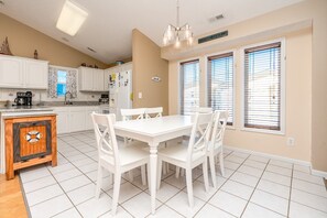A kitchen with white cabinets, a dining table with chairs, a wooden cabinet with a 'WELCOME' sign, and a 'BEACH HOUSE' sign on the wall. - Over The Moon - 4 BR home, Oceanfront B-Lot with Amazing Views! Dog Friendly! (Surf City)
