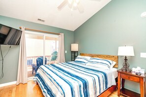 A bedroom with a bed, a television, a nightstand, and a window with curtains. - Over The Moon - 4 BR home, Oceanfront B-Lot with Amazing Views! Dog Friendly! (Surf City)