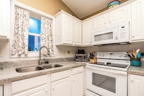 A kitchen with white cabinets, a double sink, a microwave, a toaster, and a stove. - Over The Moon - 4 BR home, Oceanfront B-Lot with Amazing Views! Dog Friendly! (Surf City)