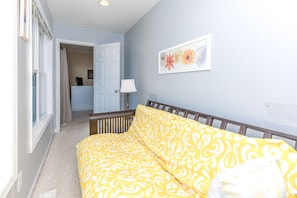 A room with a bed, a door, a wall-mounted lamp, and a framed floral artwork. - Over The Moon - 4 BR home, Oceanfront B-Lot with Amazing Views! Dog Friendly! (Surf City)