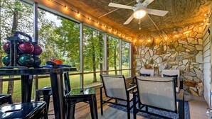 A covered outdoor area with a stone wall, a ceiling fan, and string lights. - Blue Ridge View | Pet Friendly, Deck, Grill + EV Charger (Marion)