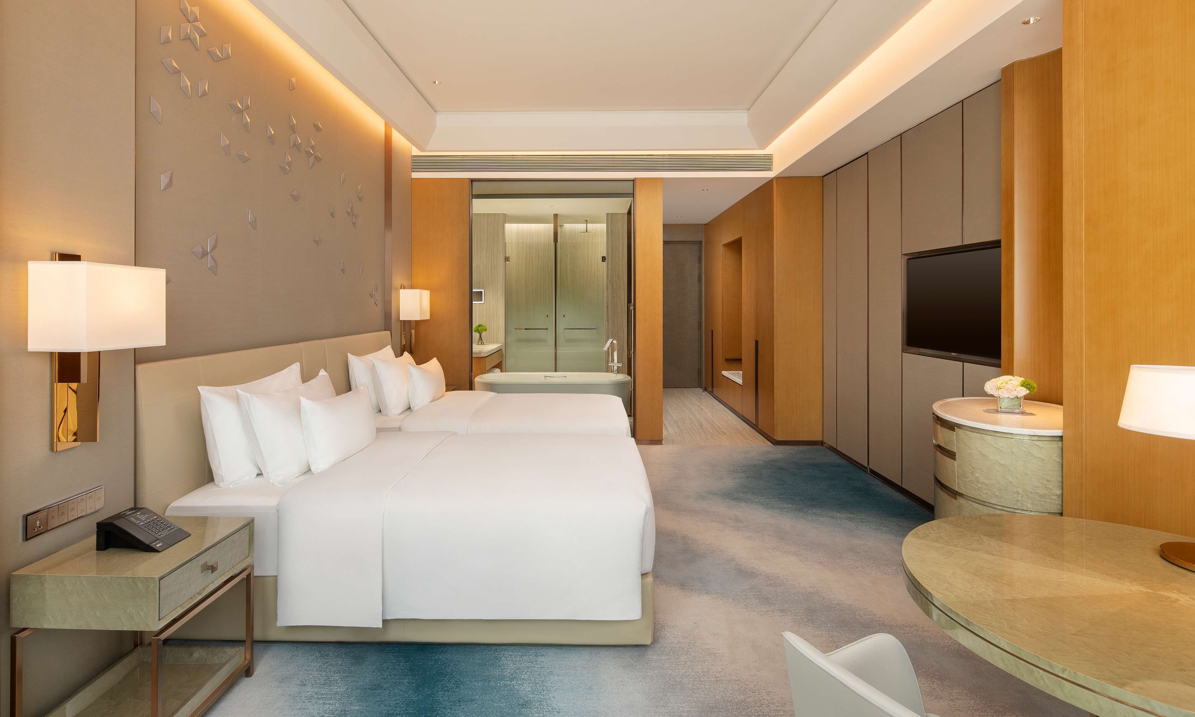 Une chambre d’hôtel avec un grand lit, des tables de chevet, une télévision et une salle de bain visible à travers une porte ouverte.