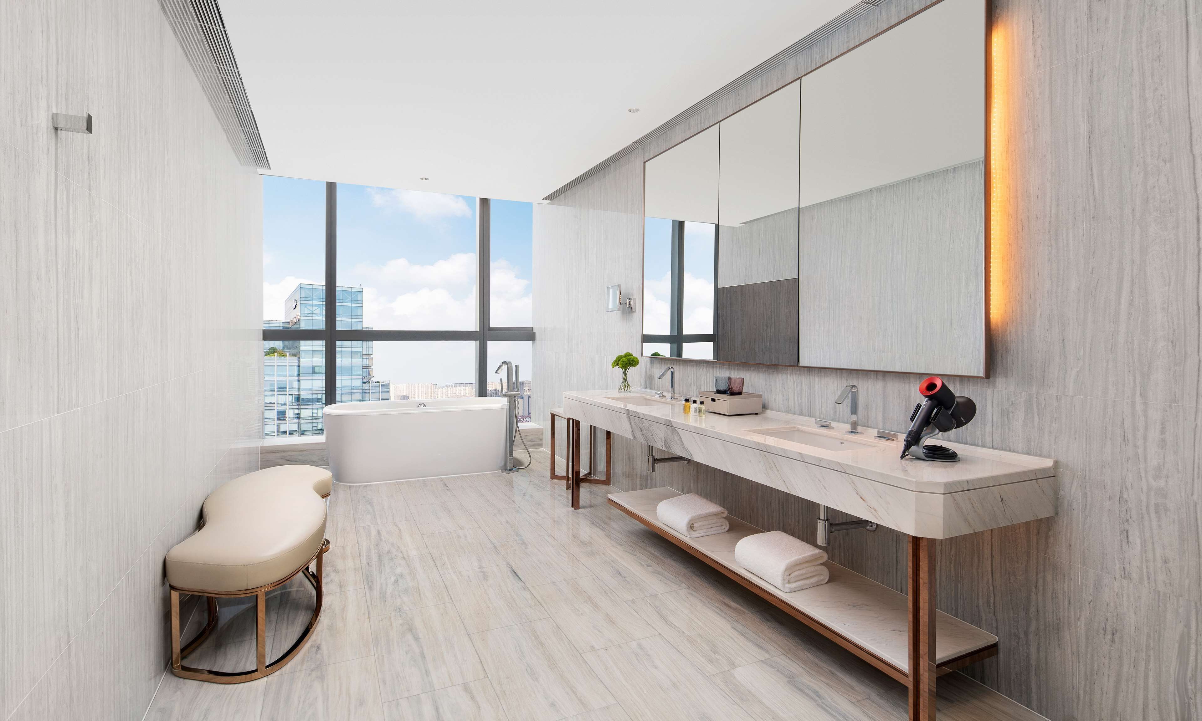 A modern bathroom with a freestanding bathtub, a large mirror, and a vanity with a towel rack.