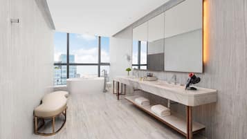 A modern bathroom with a freestanding bathtub, a large mirror, and a vanity with a towel rack.