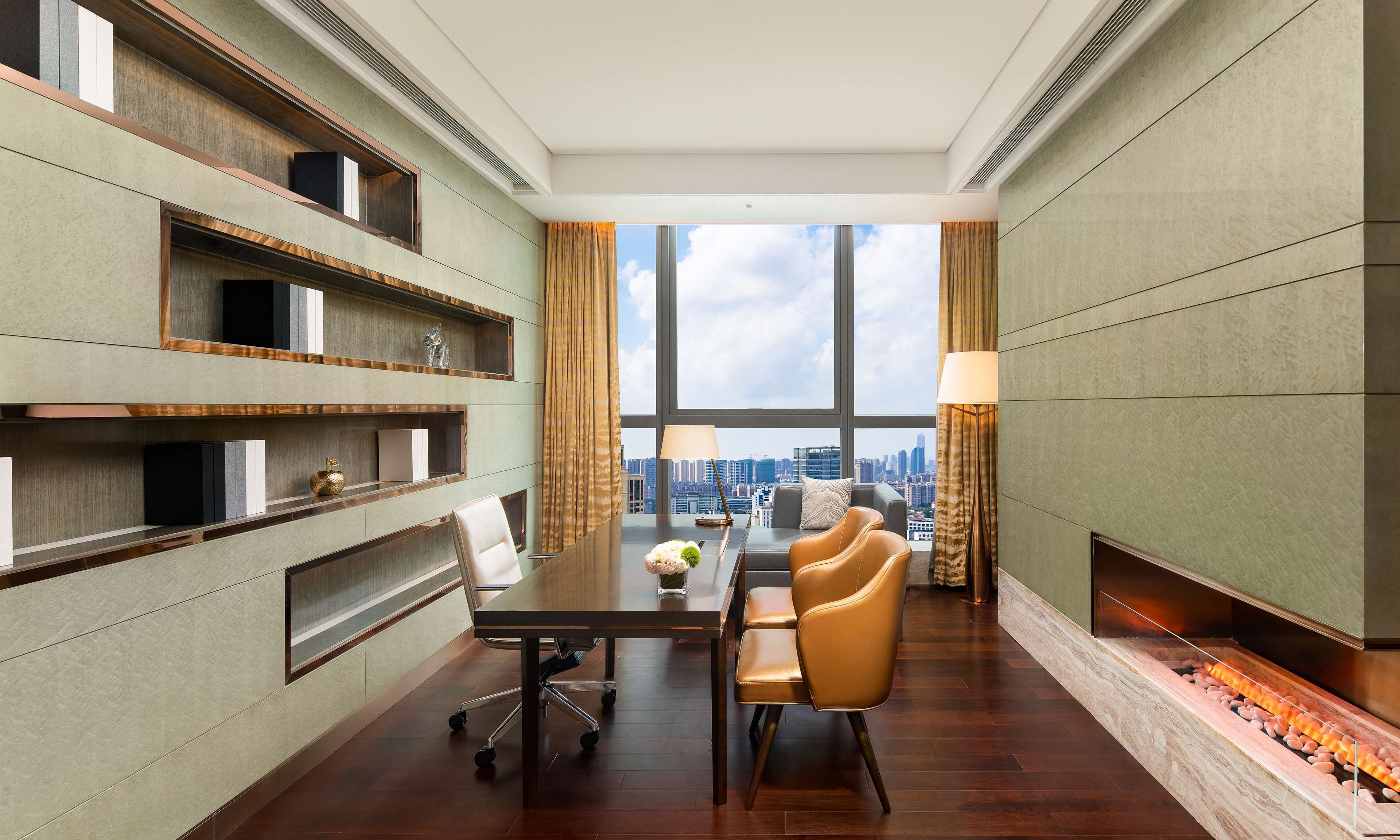A modern hotel room with a large window, a dining area with a table and chairs, and a fireplace.
