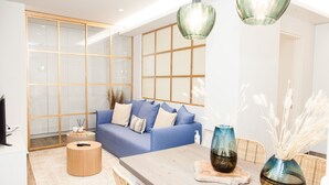 Ein modernes Wohnzimmer mit einem blauen Sofa, einem Holztisch und dekorativen Vasen.