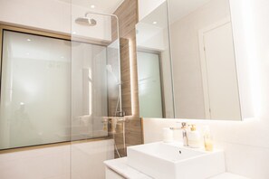 A modern bathroom with a glass-enclosed shower, a white sink with toiletries, and a large mirror. - Full renovated adorable apt in Athens (Athens)