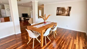 A dining area with a wooden table, white chairs, and a painting on the wall. - Wagon Holiday Home - modern home in great Abbey location! (BROADWATER)