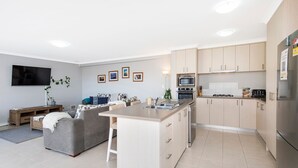 Een moderne keuken met een centraal eiland, inbouwapparatuur en licht houten kastjes.
