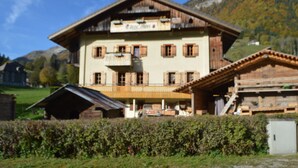 Un edificio grande de madera de varios pisos, con balcones, techo inclinado y montañas al fondo.