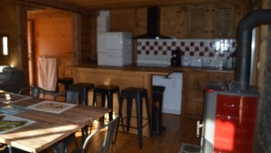 Un interior de madera con cocina, que incluye estufa, refrigerador y salpicadero de azulejos.