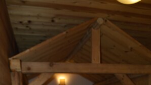 Un dormitorio tipo cabaña de madera con una cama individual, cabecera e iluminación montada en la pared.
