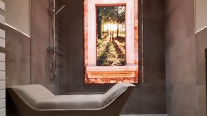 A modern bathroom with a bathtub, a shower, and a window with a forest view. - Chic apartment (Altershausen/Münchsteinach)