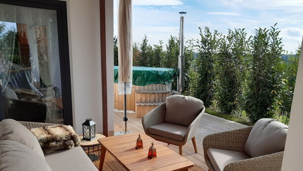 A cozy outdoor seating area with wicker furniture, a wooden table, and a lantern. - Chic apartment (Altershausen/Münchsteinach)