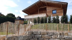 A wooden house with a balcony, a stone wall, and a fence. - Chic apartment (Altershausen/Münchsteinach)