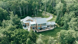 A large, two-story house with a covered patio and a swimming pool, surrounded by dense forest. - Coastal Waterfront Retreat with Sauna, Kayaks & Fire Pit, Freeport, Near LL Bean (Freeport)
