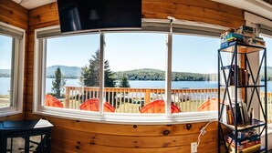 Uma cabana com uma grande janela em arco, com vista para um lago e uma floresta.