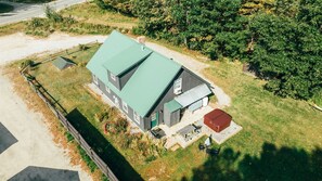 A two-story building with a green roof, a small attached garage, and a red-roofed structure. - Sunday River Chalet w/ Hot Tub, Fire Pit & River Access Near Ski Lifts (Bethel)