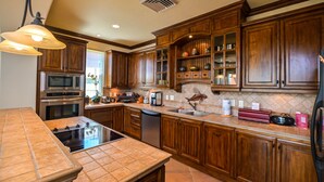 A kitchen with wooden cabinets, a built-in oven, a microwave, a stove, and a sink. - Montebello 2C 3 bdr Ocean View in Los Suenos (Playa Herradura)
