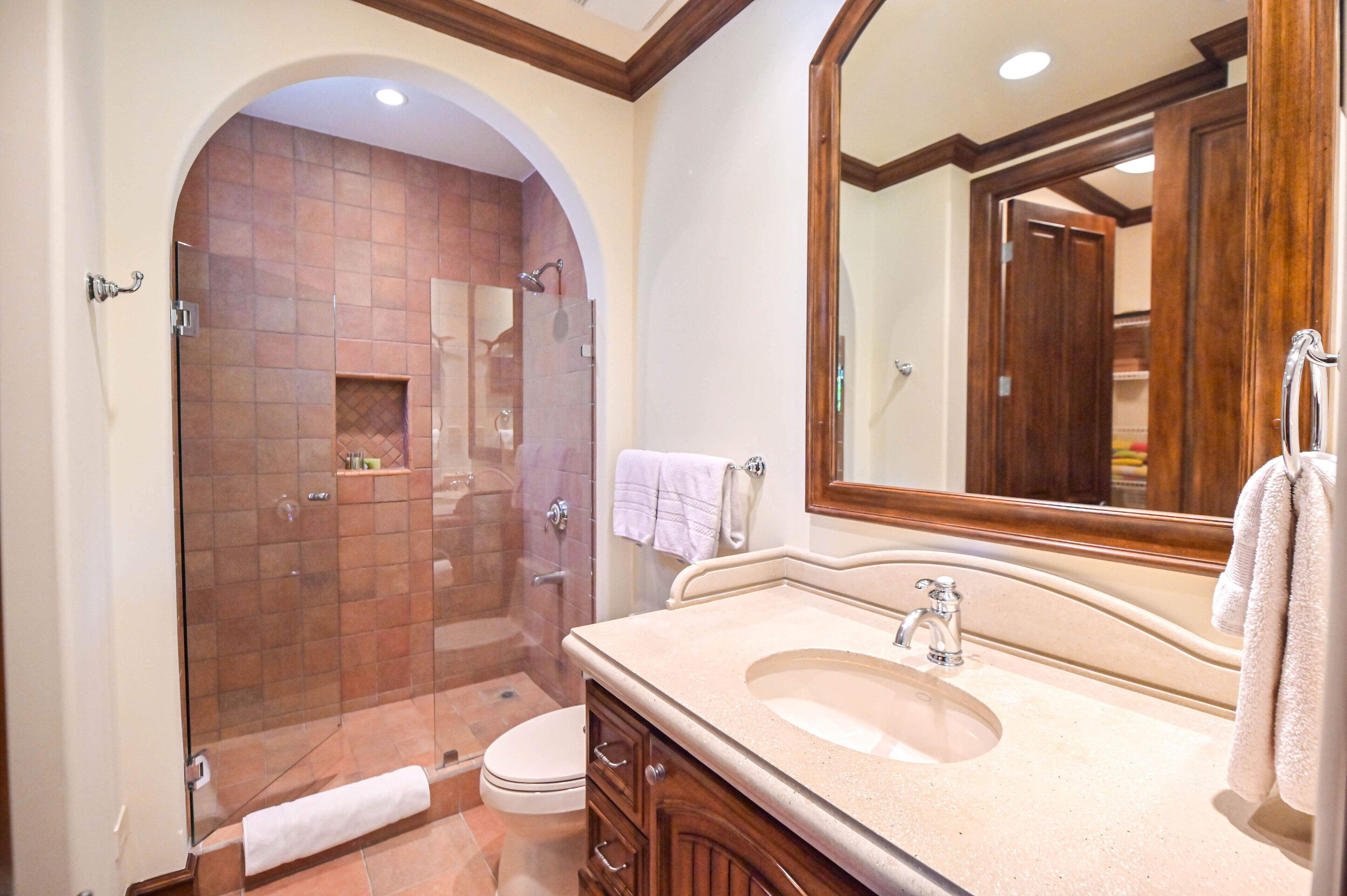 A bathroom with a glass-enclosed shower, a sink with a mirror, and a toilet.