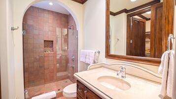 A bathroom with a glass-enclosed shower, a sink with a mirror, and a toilet.