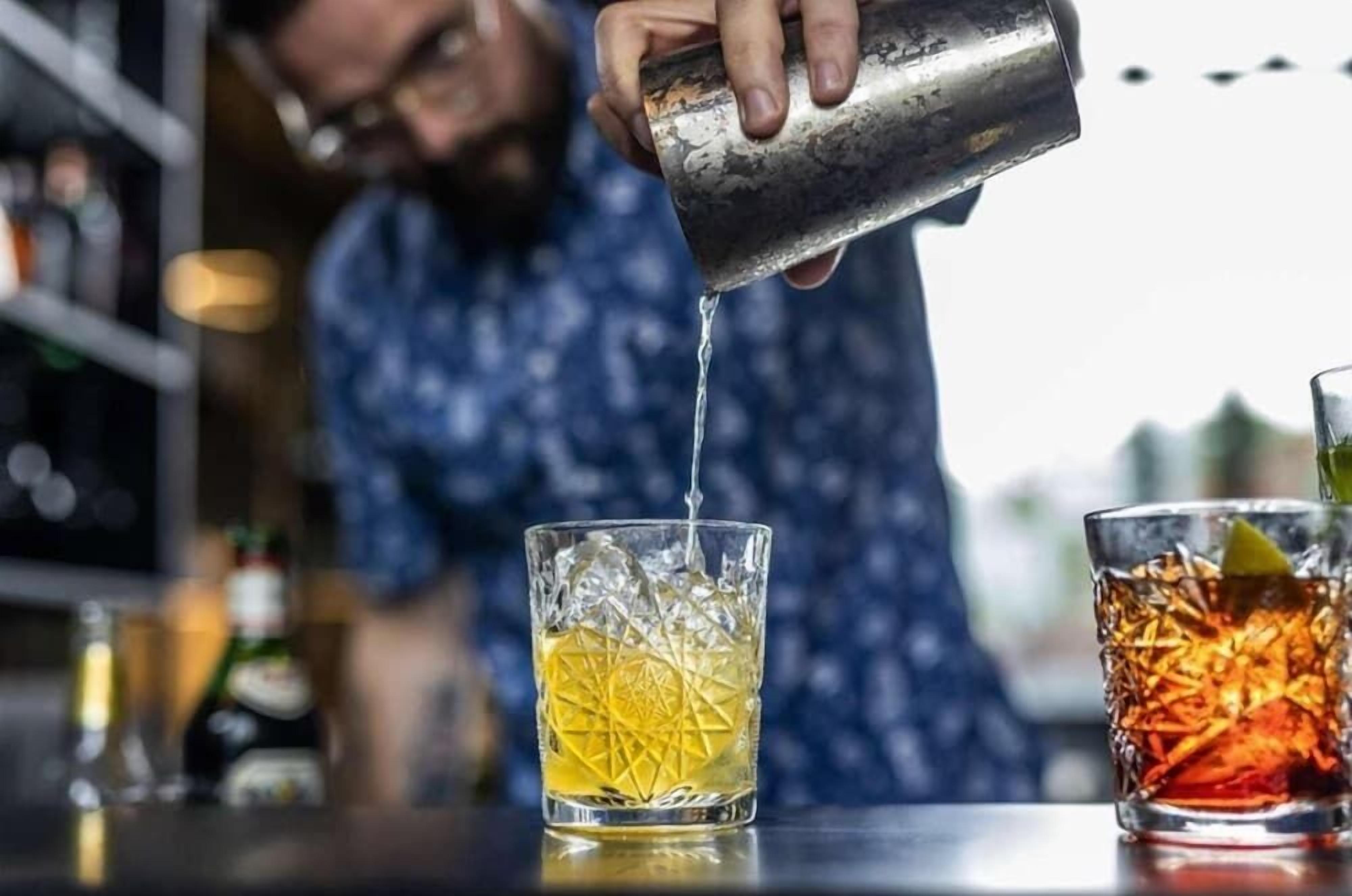 A person pouring a drink into a glass with a geometric pattern.