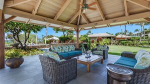 A covered outdoor seating area with wicker furniture and a ceiling fan. - Hale Inu Waina: Spacious 2BR condo in Waikoloa with scenic views. (Waikoaloa)