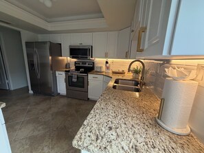 Eine moderne Küche mit Edelstahlgeräten, Granit-Arbeitsplatten und weißen Schränken.