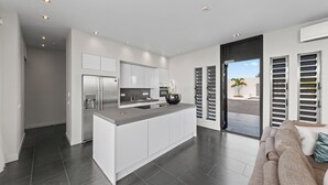 Una cocina moderna con armarios blancos, una isla central y un amplio ventanal.