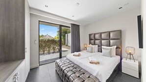 Un dormitorio moderno con una cama grande, un ventanal corredero a un área exterior y un diseño minimalista.