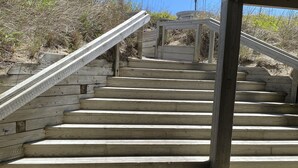 Una escalera de madera que sube a un espacio cubierto con un paraguas rojo y blanco a rayas.