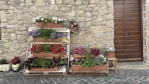 Een stenen muur met een houten deur en bloempotten op een houten standaard.