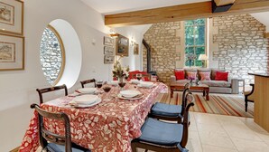 Comedor con una mesa lista para cuatro personas, rodeado de paredes de piedra y una chimenea.