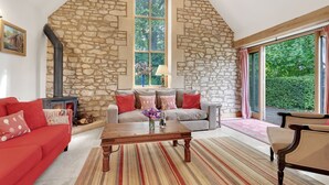 Una sala de estar acogedora con pared de piedra, chimenea, sofá y un ventanal grande.