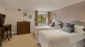 A bedroom with two beds, a dresser, a television, and a window with curtains. - Tom's Barn - sleeps 10 guests  in 5 bedrooms (Cheltenham)