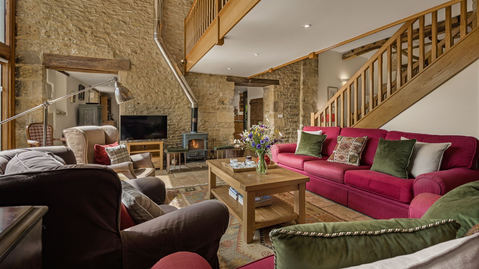 A living room with a stone wall, a red sofa, a wooden coffee table, and a fireplace.
