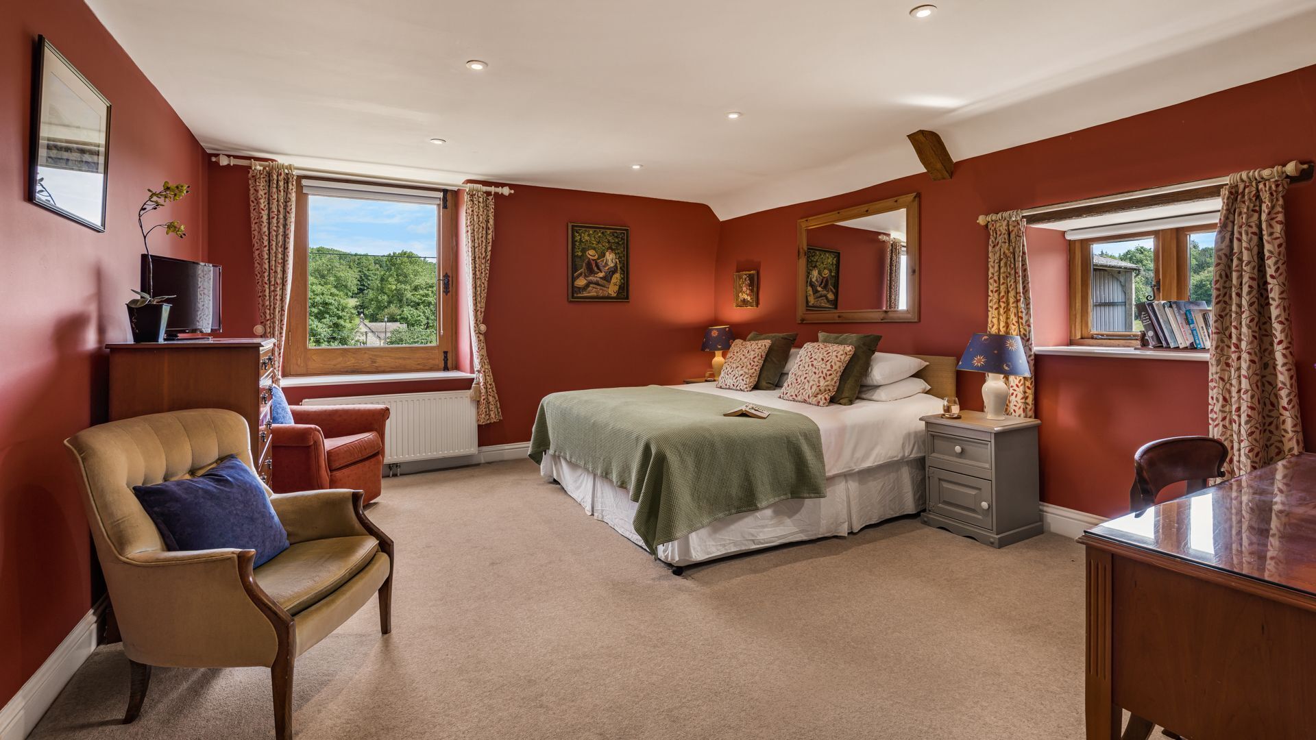 A bedroom with a bed, bedside tables, a chair, a desk, and a window with curtains.