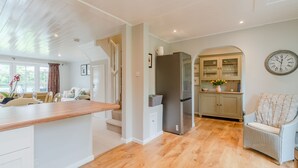 A spacious kitchen with a wooden countertop, a dining area with a table and chairs, and a cozy seating area with a chair. - Mayfly Lodge - sleeps 6 guests  in 3 bedrooms (Cotswold Lakes)