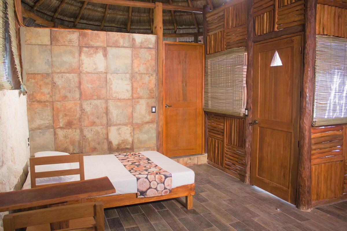 Una habitación con cama, muebles de madera, pared con azulejos y puerta de madera.