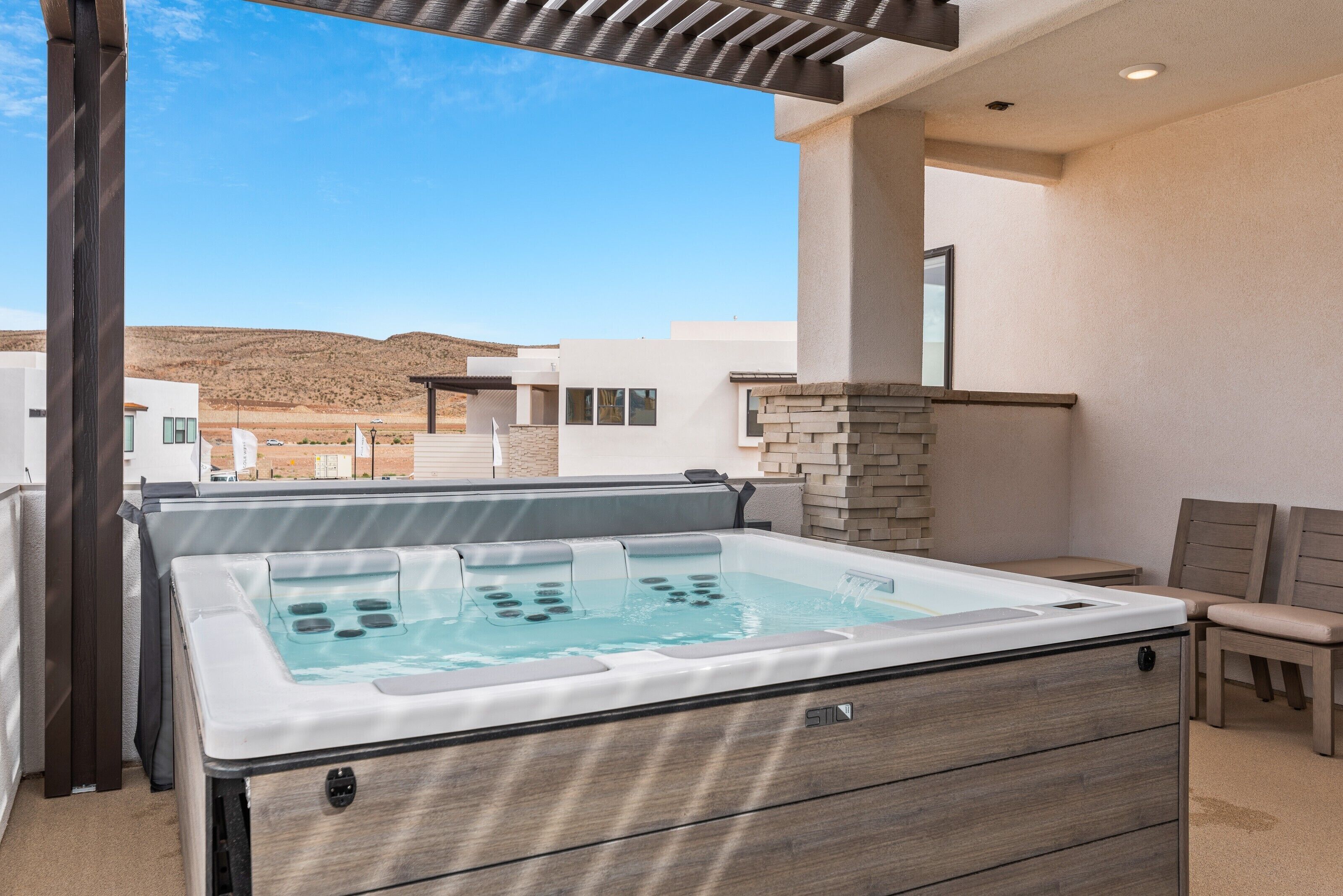A spa area with a hot tub, wooden deck, and a view of a desert landscape.